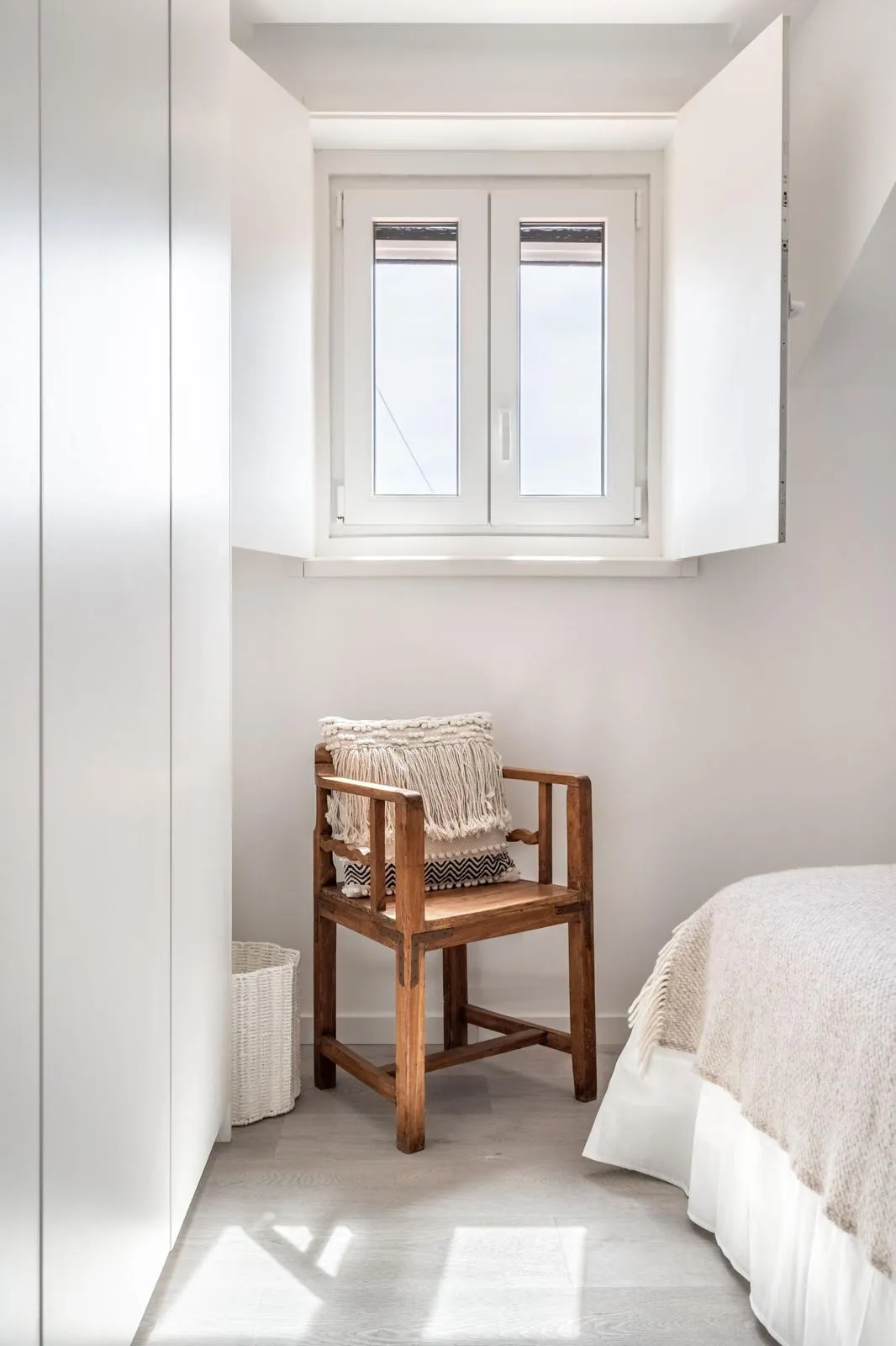 Bedroom with built-in wardrobe and open casement window revealing green tree foliage