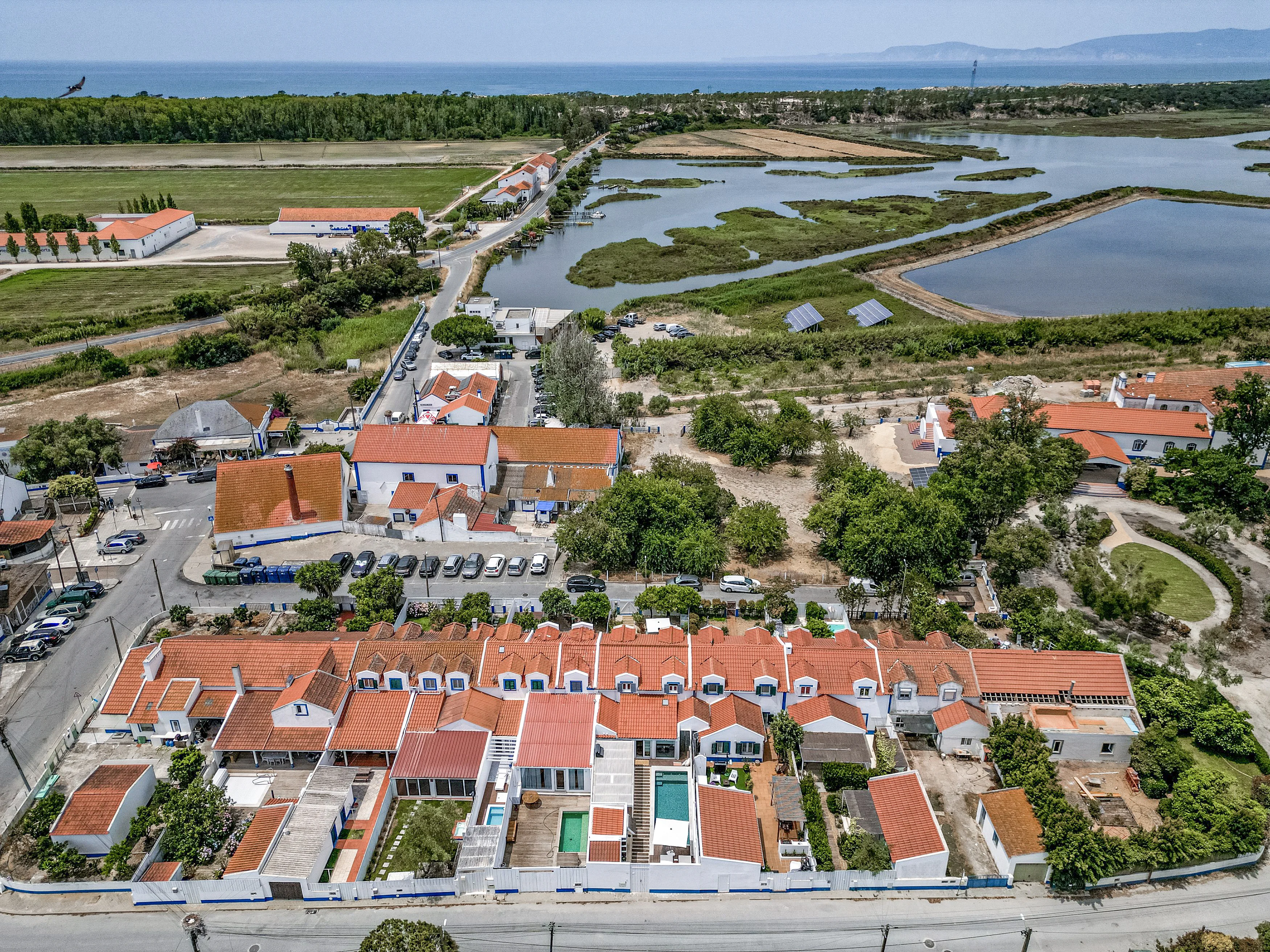 Aerial view of a coastal village with terracotta rooftops and salt pans near Comporta