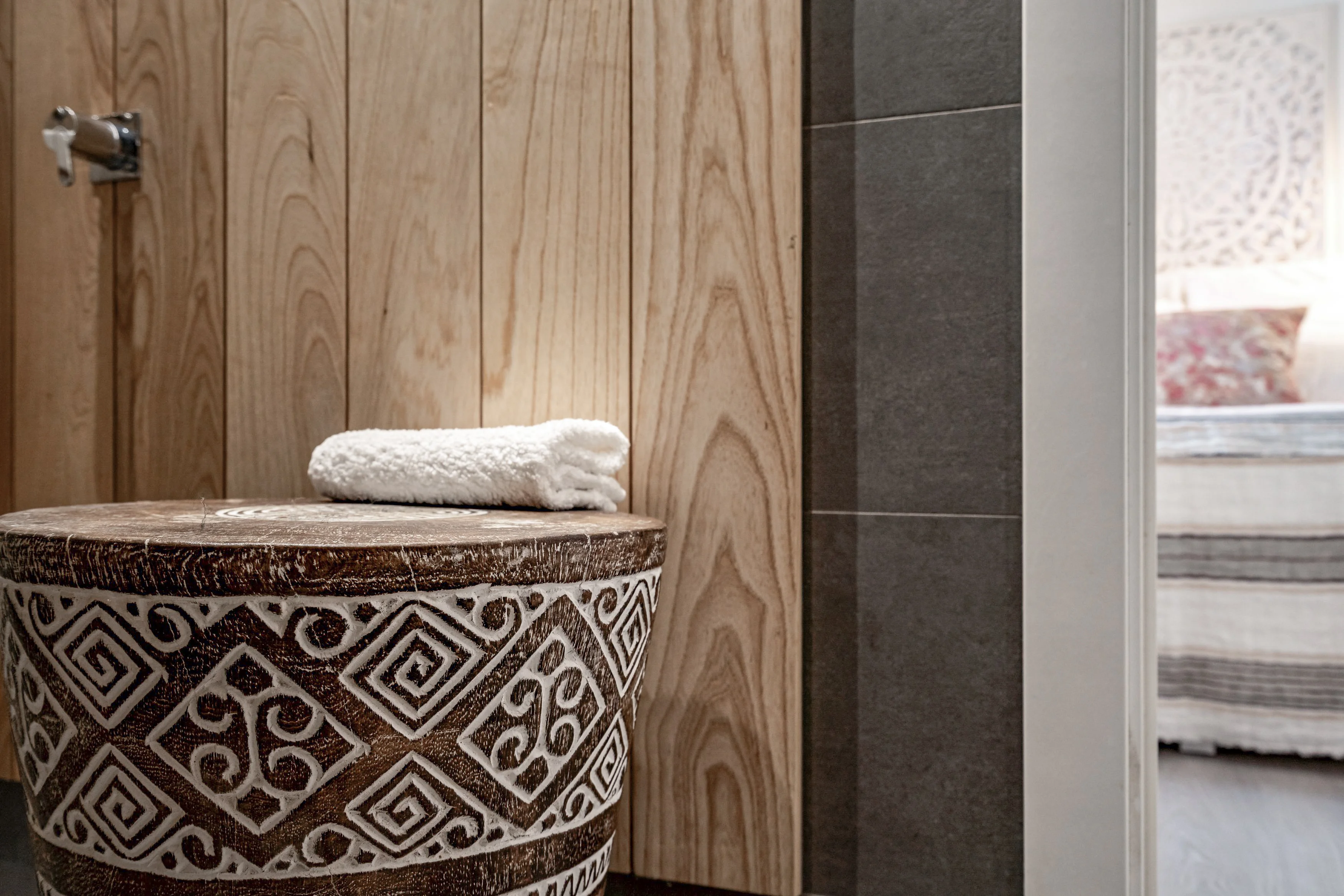 Carved wooden stool with towel at bathroom-to-bedroom transition