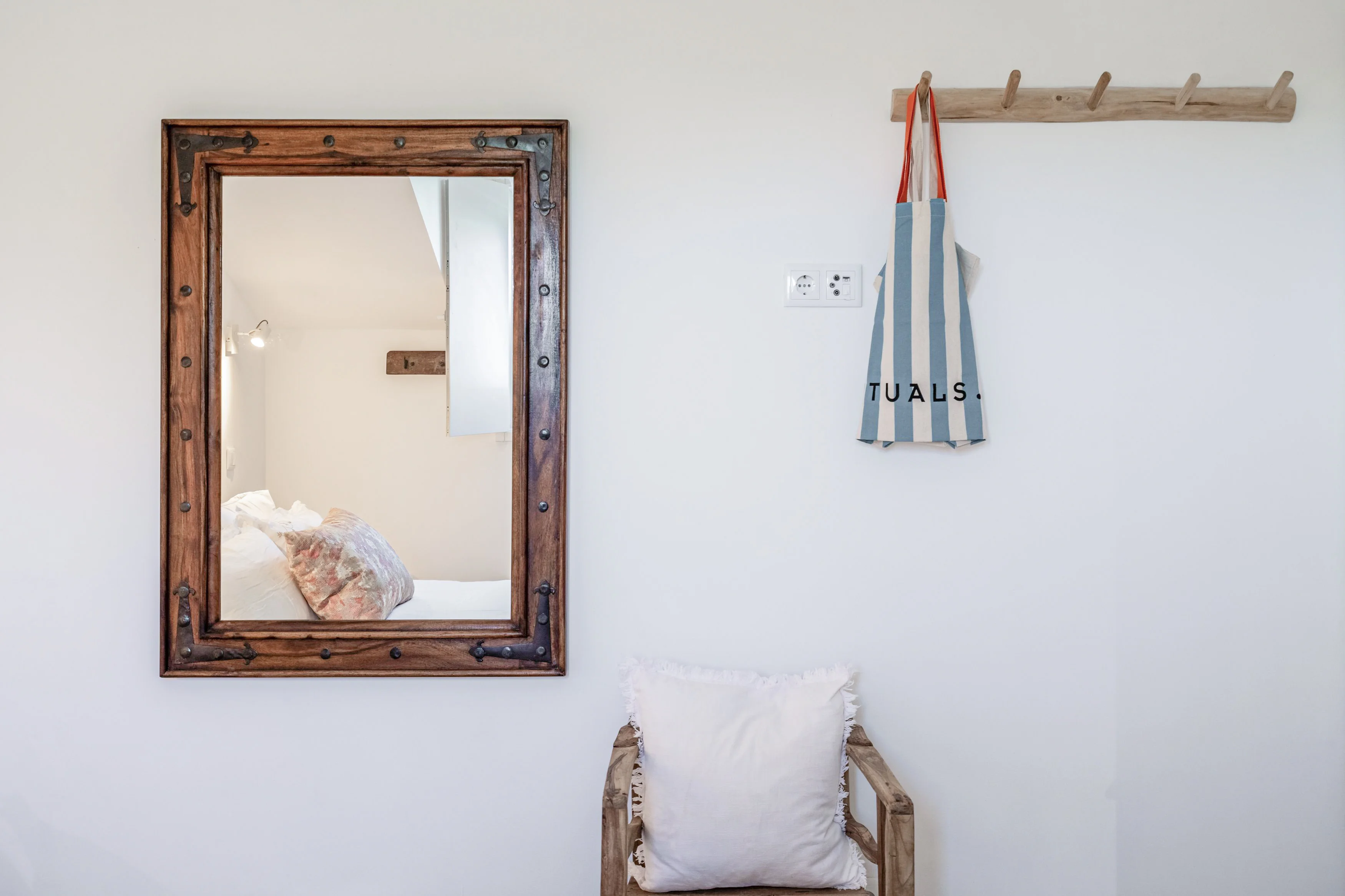 Bedroom detail with rustic studded mirror, driftwood coat rack and branch-wood chair