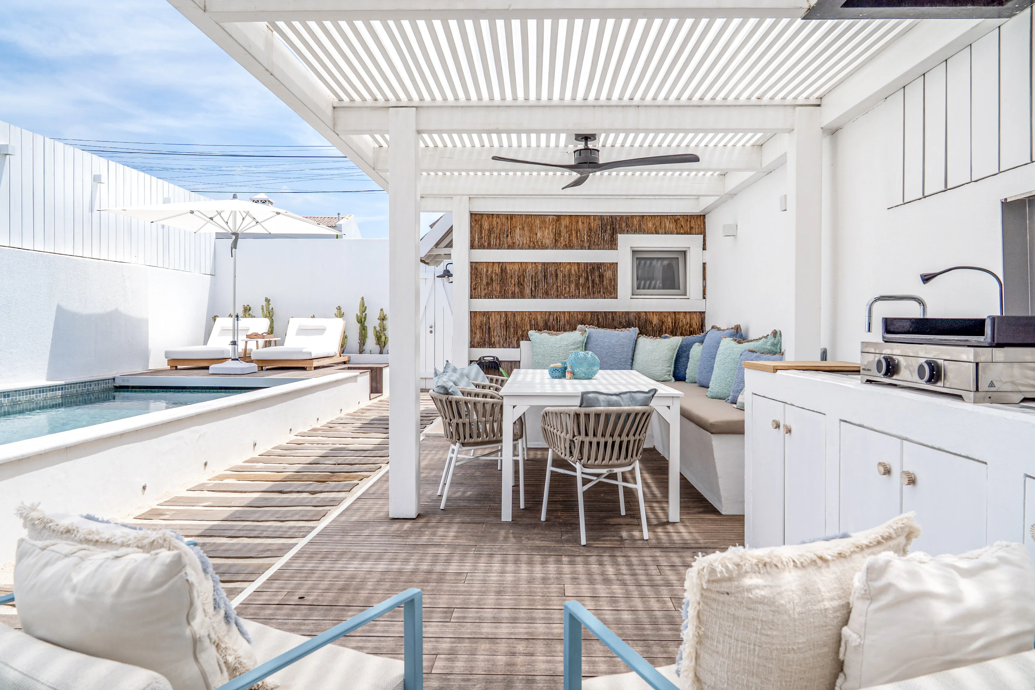 Covered outdoor patio with wooden dining table, wicker chairs, pendant lights and garden