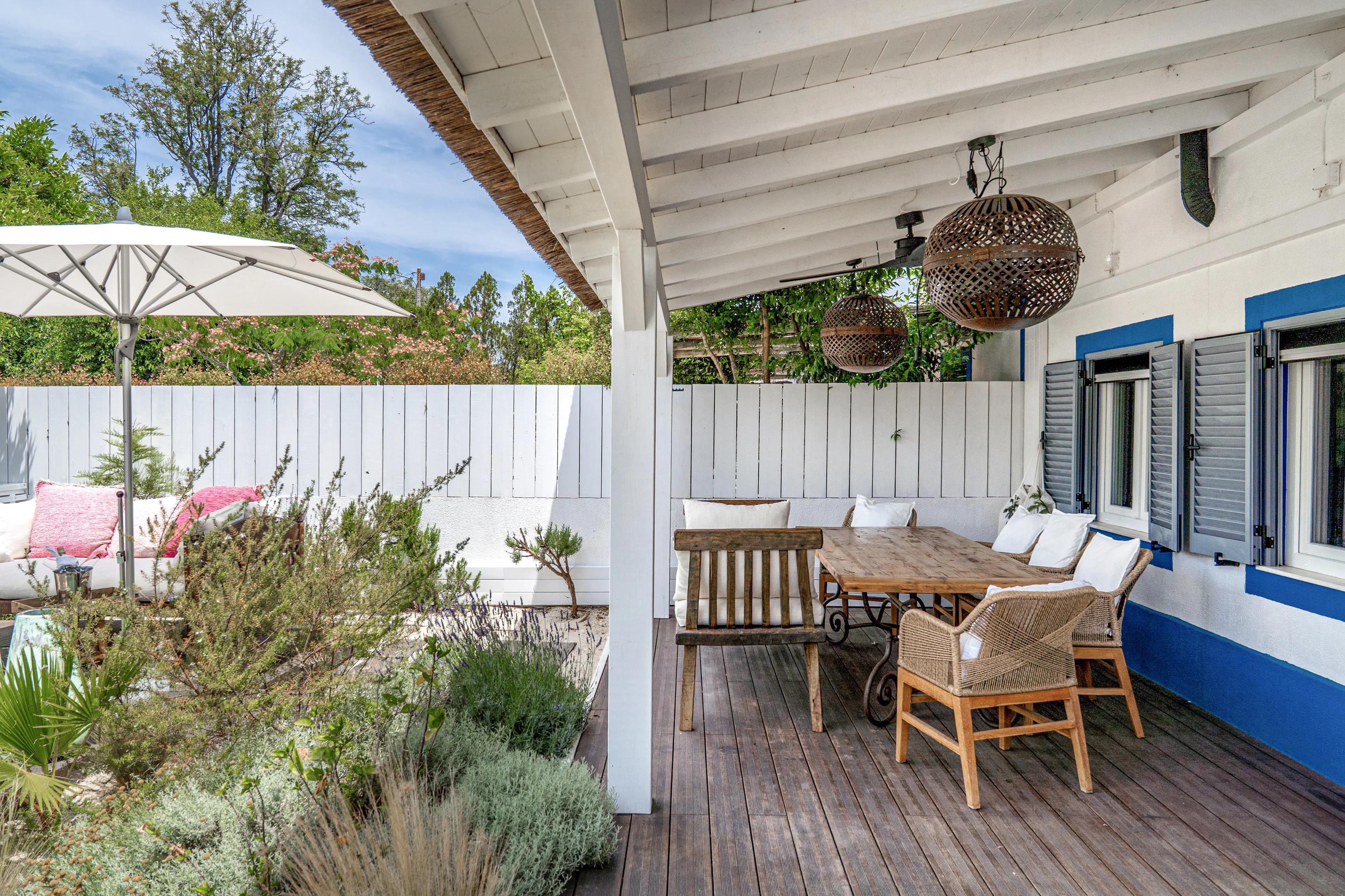 Covered terrace with parasol, dining table and wicker chairs at Comporta Village House