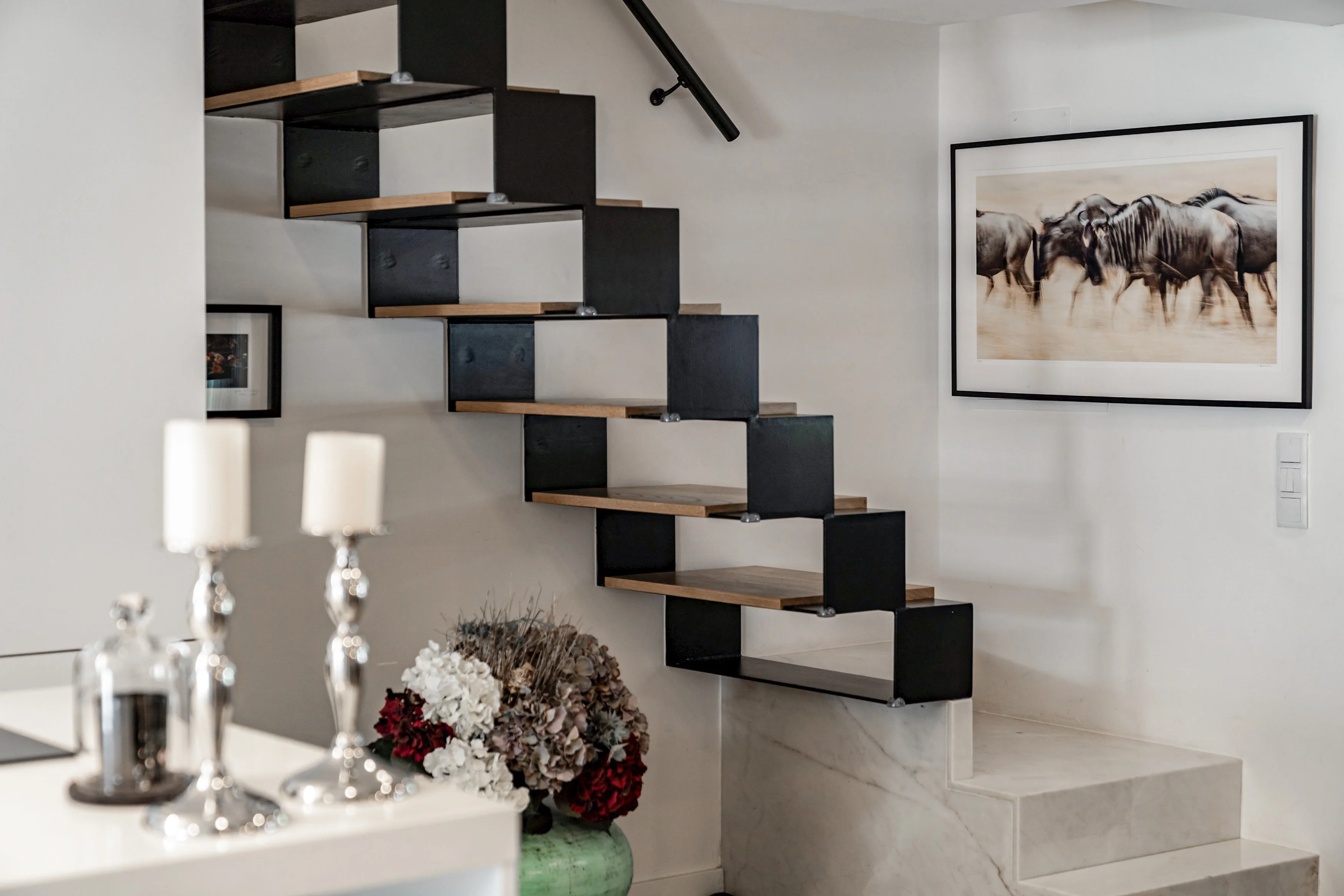 Modern floating staircase with black metal sides, wooden treads and marble base steps