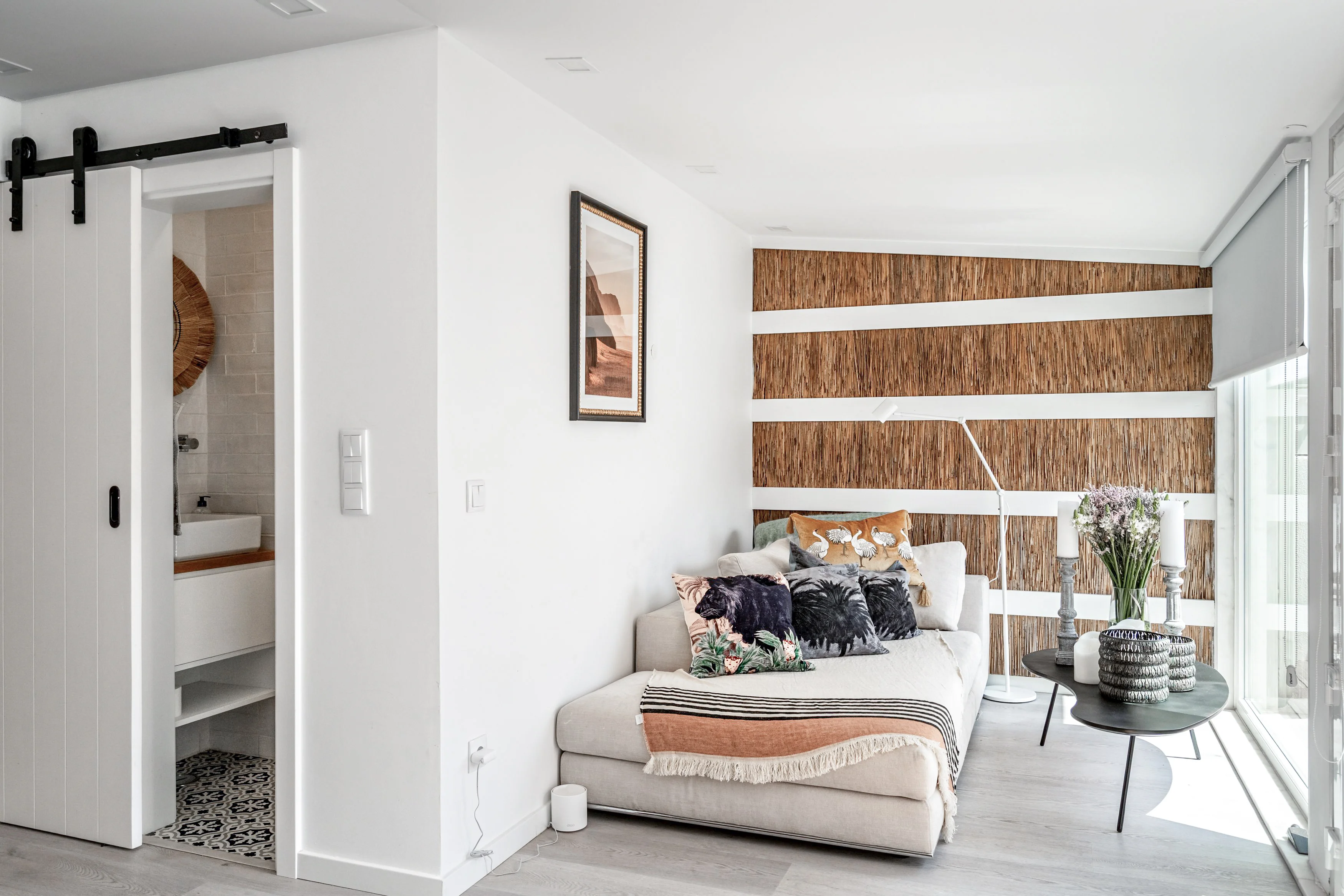 Living room with reed accent wall, decorative pillows and sliding barn door to bathroom