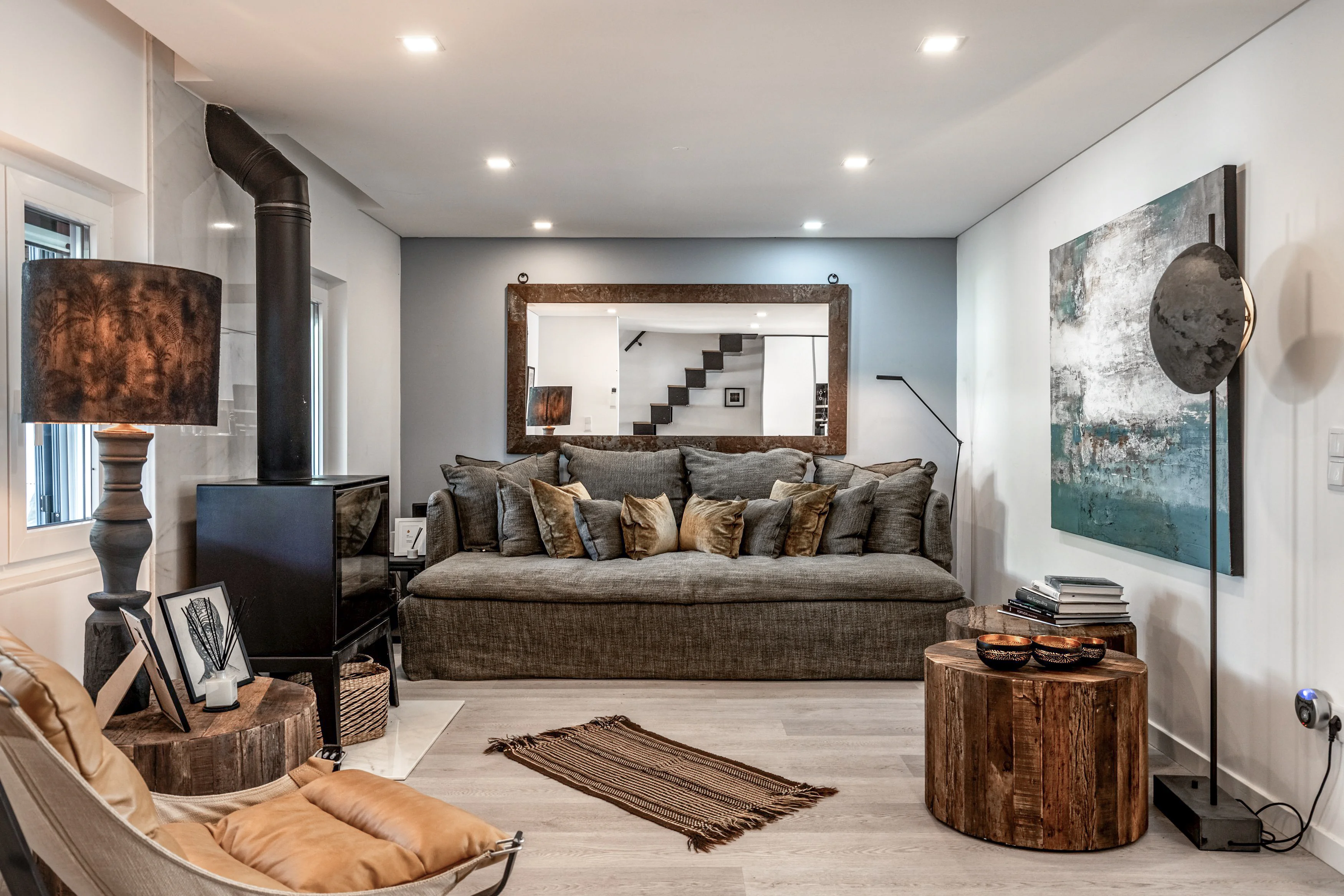 Living room with leather chaise lounge, tree-stump tables and wood-burning stove