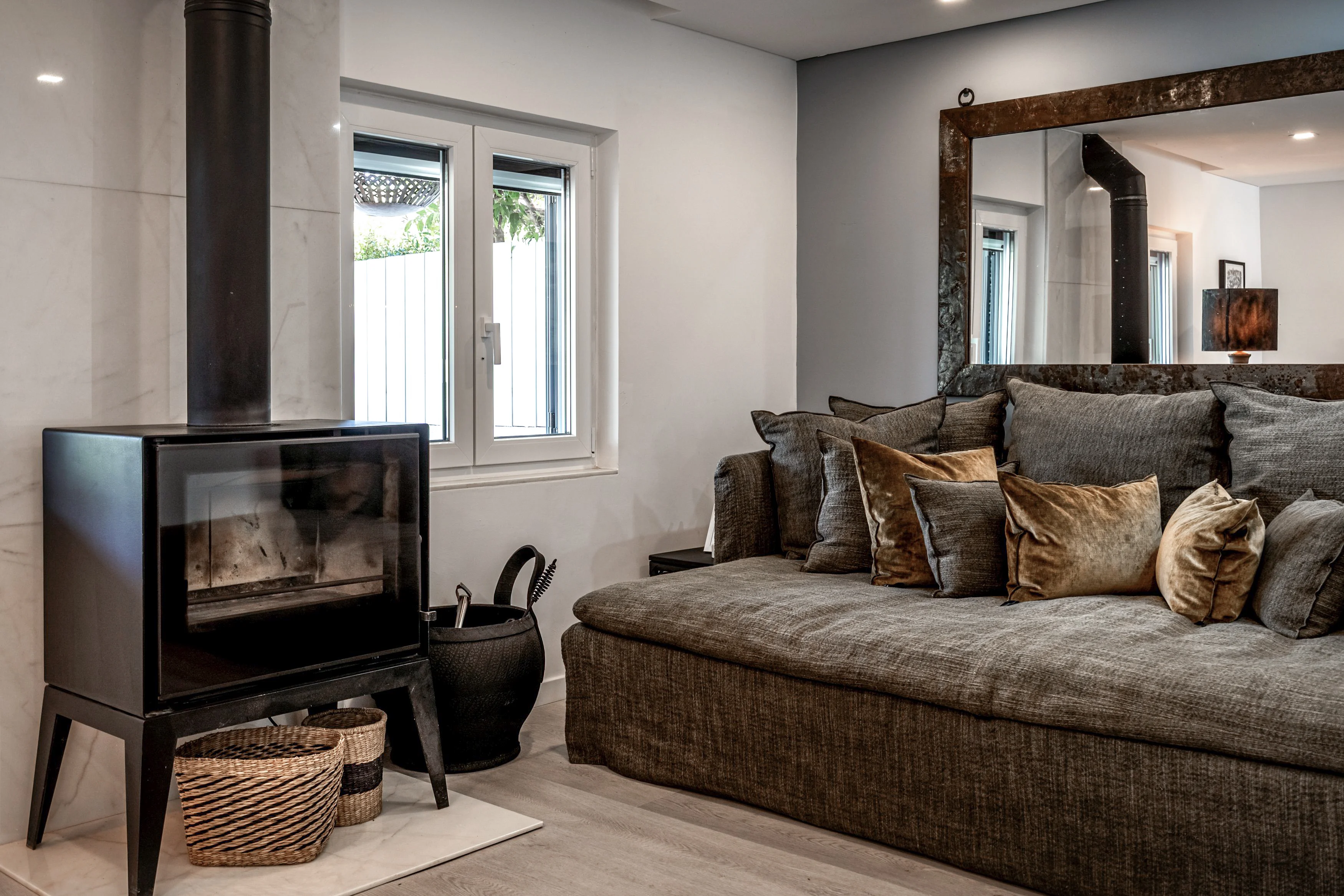 Living room with dark sectional sofa and black wood-burning stove on marble hearth