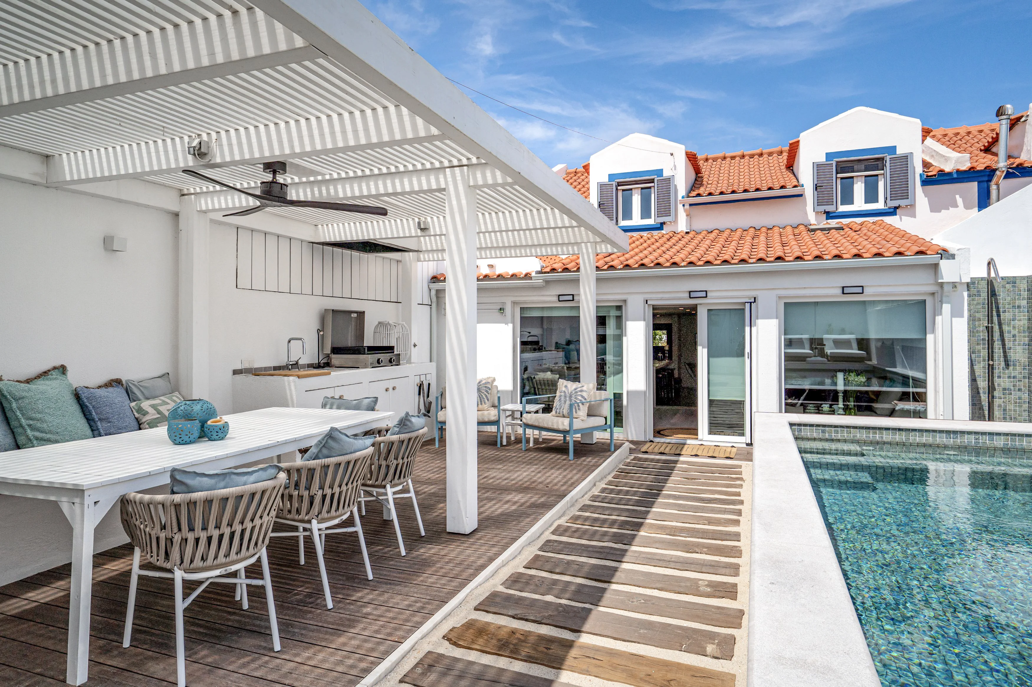 Outdoor patio with pergola, outdoor kitchen, pool, glass sliding doors and blue shutters