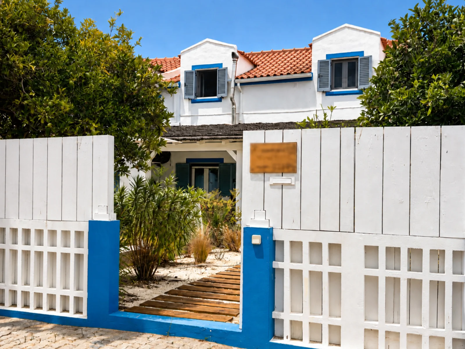Street view of whitewashed Portuguese houses with blue base trim, house number 13 and terracotta roof