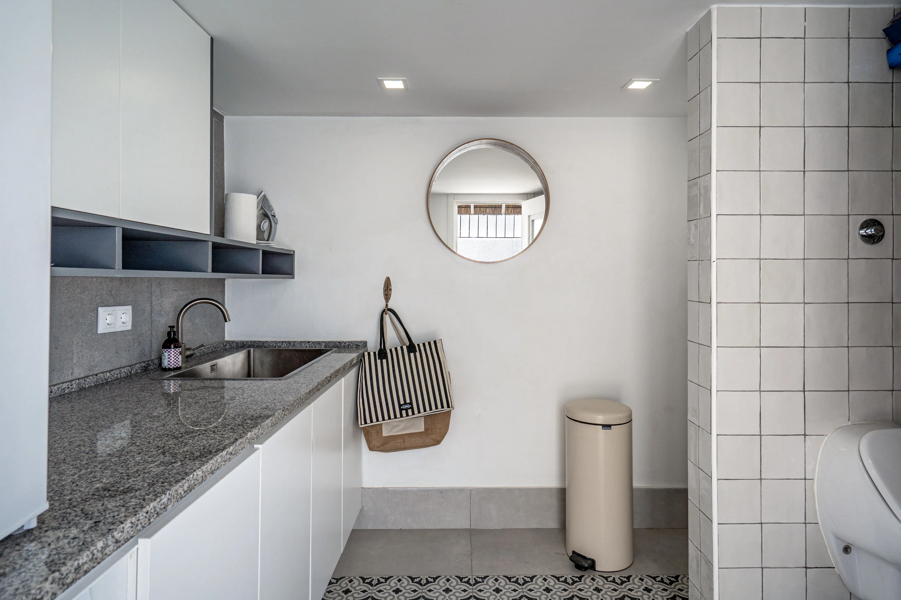 Utility room with sink, shelving, copper mirror and patterned cement tile border