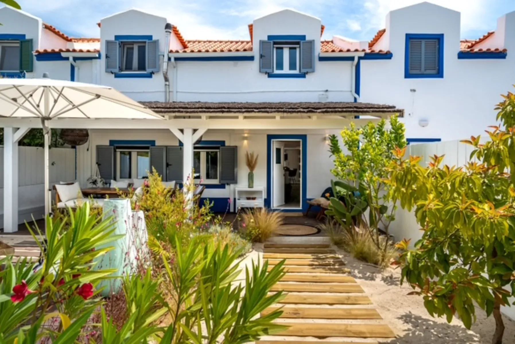 Whitewashed Comporta village house with blue trim, terracotta roof and wooden boardwalk entrance